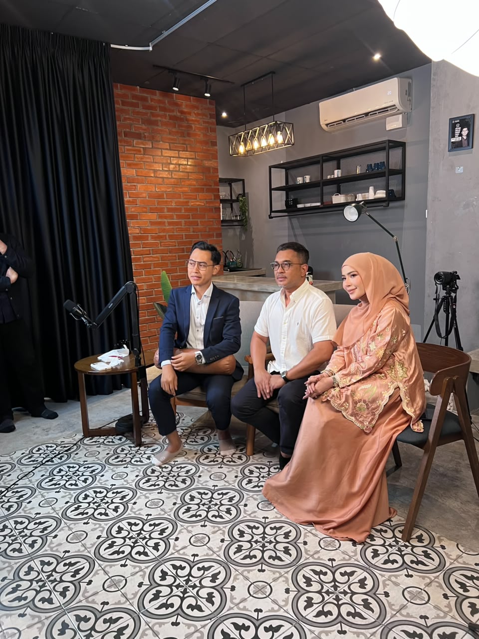 Madammu Eriyca Baiduri duduk bersama dua orang panel dalam sesi rakaman podcast, mewakili momen di sebalik perkongsian peribadi untuk Diari Madammu.